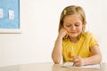 Young Girl Smiling in Classroom Writing on Paper Royalty Free Stock Photo