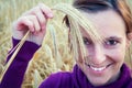 Young girl smiling with ear in her hand, on a wheet field Royalty Free Stock Photo