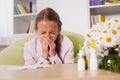 Young girl sneezing at home with paper towel prepared to blow he