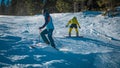 Young girl on snowboard helps a skier