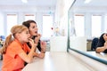 Young girl in speech therapy office. Mirror reflection of young girl exercising correct pronunciation with speech therapist. Royalty Free Stock Photo