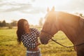 Beautiful young girl with her horse at sunset