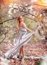 Young girl spinning in motion in a silver dress with a long train in the garden. Concept of advertising and people. Fashionable