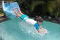 Young girl splashing into pool after going down water slide Royalty Free Stock Photo