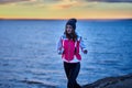 A young girl in a sports hat and jacket makes a morning jog on the embankment in the morning before the dawn of the sun. Royalty Free Stock Photo