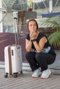 A young girl is squatting with a suitcase near the window. Perhaps she missed her plane or train, is very worried, or is waiting Royalty Free Stock Photo