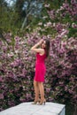 Young girl stand in front of sakura tree. Spring outside. Pink Blossom tree Royalty Free Stock Photo