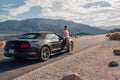 Young girl standing by the black Ford Mustang GT