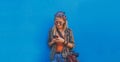 Young girl standing by the blue background holding a smartphone - A hipster stylish girly smiling and checking out social media