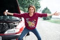 Young girl standing at the broken car and looking for help