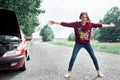 Young girl standing at the broken car and looking for help Royalty Free Stock Photo