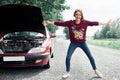 Young girl standing at the broken car and looking for help Royalty Free Stock Photo