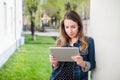 Young girl standing on the college campus yard with the tablet h Royalty Free Stock Photo