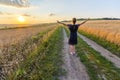 Young girl standing on dirt gravel road in wheat field at sunset Royalty Free Stock Photo