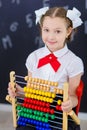 Young girl standing in front of chalkboard brick wall with letters on it wearing school uniform with huge pensil yellow color