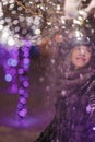 Young girl standing in front of christmas tree lights at night w Royalty Free Stock Photo