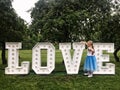 Young girl standing at love neon letters in a park