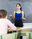 Young girl is standing near blackboard and writing solution of the homework in the classroom Royalty Free Stock Photo