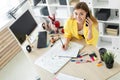 A young girl is standing near a table, talking on the phone, holding a pencil in her hand and making notes in a notebook Royalty Free Stock Photo