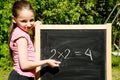 Young girl standing next to black slate