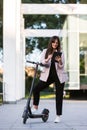 A young woman standing next to her electric scooter with a tablet in her hands Royalty Free Stock Photo