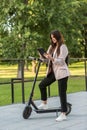 A young woman standing next to her electric scooter with a tablet in her hands Royalty Free Stock Photo