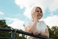 A young girl is standing outdoors in a park and talking on the phone, smiling. Girl against the sky Royalty Free Stock Photo