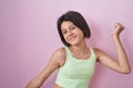 Young girl standing over pink background dancing happy and cheerful, smiling moving casual and confident listening to music Royalty Free Stock Photo