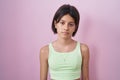 Young girl standing over pink background looking sleepy and tired, exhausted for fatigue and hangover, lazy eyes in the morning