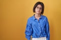 Young girl standing over yellow background relaxed with serious expression on face Royalty Free Stock Photo