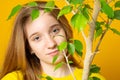 Young girl standing with pleased smile and holding flower pot, admiring green large plant, loves gardening and nature