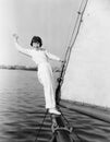 Young girl standing on a sailboat and waving Royalty Free Stock Photo