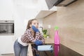 A young girl is standing thoughtfully in the kitchen in protective gloves.A tired young cleaner rests in the kitchen after Royalty Free Stock Photo