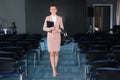 A young girl stands in the conference room. The concept of a business trip. Training and lectures. An empty room with many chairs