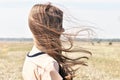 Young girl stands in the field and wind flutters her hair