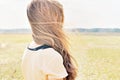 Young girl stands in the field and wind flutters her hair