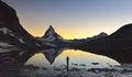 Young girl stands in front of the lake where the Matterhorn 4478m and Dente Blanche 4357m reflected in the Riffelsee