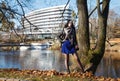 Young girl stands near river in city park on autumn day Royalty Free Stock Photo