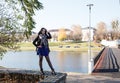 Young girl stands near river in city park on autumn day Royalty Free Stock Photo