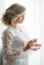 A young girl stands near the window with a cup of strong coffee. morning of the bride