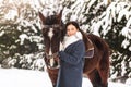 Young girl stands with a horse in the winter outdoors