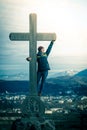 Young girl stands proud and happy on a summit cross, autumn