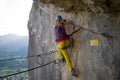 Young girl starting the via ferrata route called `Hohenweg` by stepping over a safety wire, above Bad Goisern, in Upper Austria