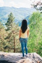 Young girl staying on the rock and looking on mountains landscape