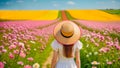 Young girl with straw hat standing in a blooming flower meadow in summertime.