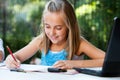 Young girl doing schoolwork with pencil outdoors. Royalty Free Stock Photo