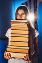 Young girl student with glasses in library smiling and carries stack of books. Exam preparation Royalty Free Stock Photo