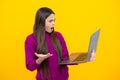 Young girl student hold computer. Funny pupil with laptop on yellow background. Back to school. Angry teenager