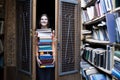 Girl student holds a large stack of books and carries a lot of literature in the library, she is preparing for study, the seller Royalty Free Stock Photo