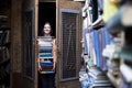 Girl student holds a large stack of books and carries a lot of literature in the library, she is preparing for study, the seller Royalty Free Stock Photo